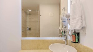 Ein Badezimmer mit großem Spiegel, Waschbecken, Dusche und Handtuchhalter.