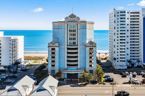 Ein mehrgeschossiges Hotel mit zentralem Atrium, Parkplatz und Blick auf den Strand.