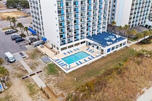 Ein Hochhaus mit Pool auf dem Dach, mehreren Balkonen und einem Parkplatz.