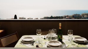 Mesa dispuesta para comer con vista al mar y edificios.
