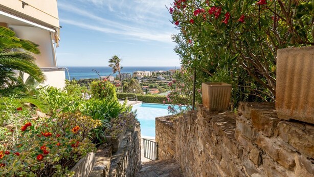 Una escalera de piedra que conduce a una piscina con vistas al océano y edificios al fondo.
