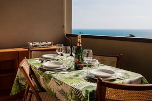 A dining table set with plates, glasses, and a bottle of champagne, overlooking the sea. - GuestHost - Cozy 32 sq m apartment, perfect for three people, located on the second floor of a former residence with elevator (NOT accessible to disabled guests).The property is located in a quiet area of ​​Sanremo and offers various condominium amen (Sanremo)