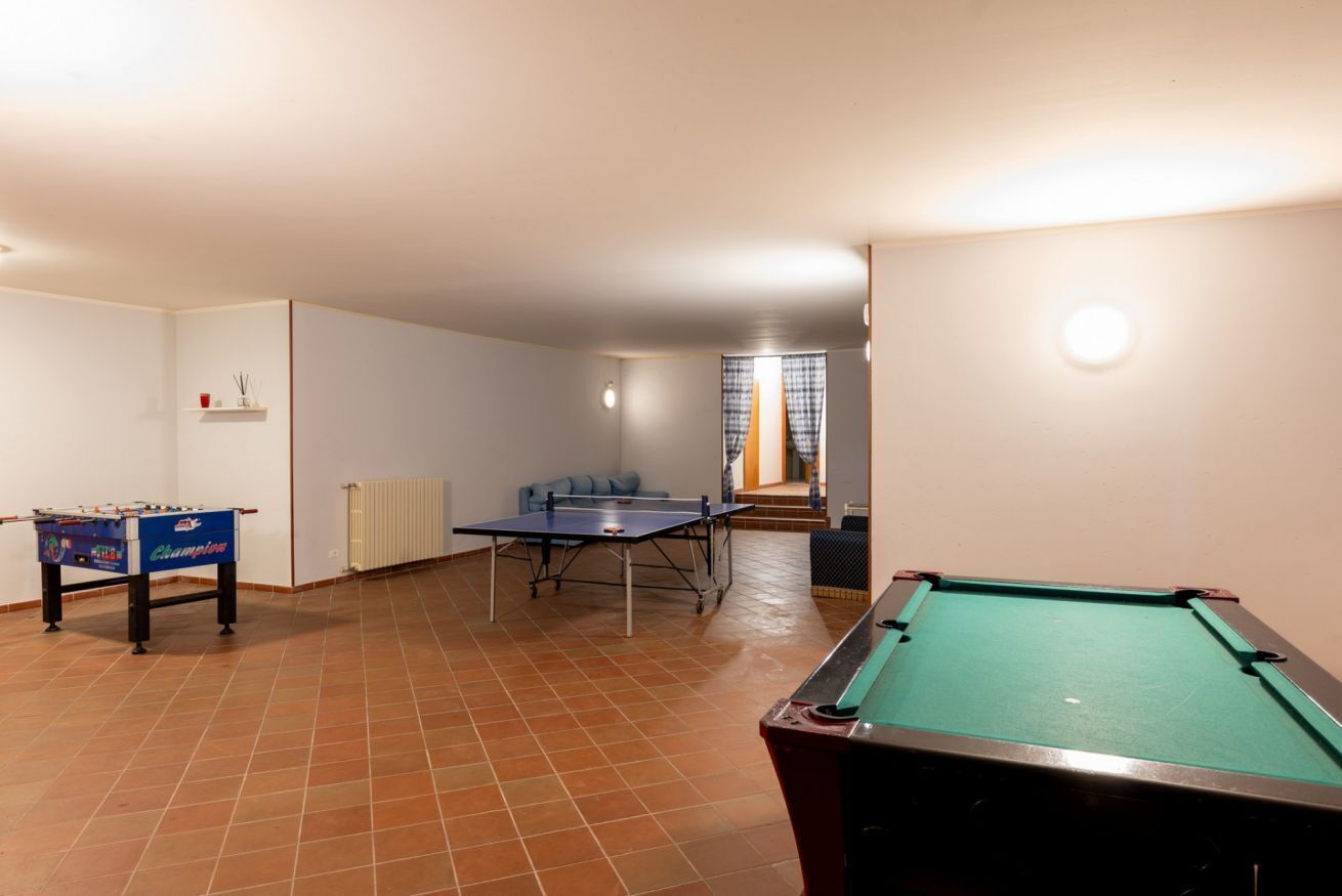 A room with a pool table, foosball table, and ping pong table.
