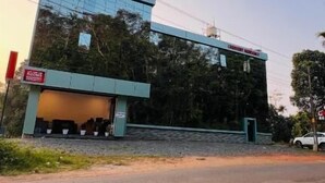 A modern building with a large glass facade, a flat roof, and a visible entrance. - Crescent Residency Wayanad (Vythiri)