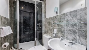 Ein modernes Badezimmer mit einer Duschkabine, einer Toilette und einem Waschbecken mit Ablagefläche darüber.