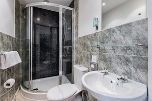 A modern bathroom with a glass-enclosed shower, a toilet, and a sink with a glass shelf above. - Double Room with Kitchen & Parking | Gorseinon Swansea (Gorseinon)