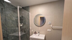 A bathroom with a glass-enclosed shower, a sink with a mirror, and a toilet. - Willa Marianna - apartamenty wakacyjne (Lądek-Zdrój)