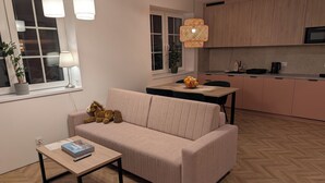 A modern living room with a sofa, a coffee table, and a dining area with a table and chairs. - Willa Marianna - apartamenty wakacyjne (Lądek-Zdrój)