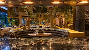 A luxurious lobby with a curved seating area, a marble floor, and a staircase with a railing.