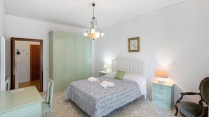 Ein Schlafzimmer mit Bett, Schreibtisch, Stuhl, Kleiderschrank und Nachttisch mit Lampe.