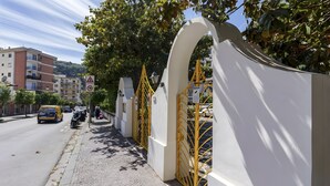Ein gepflasterter Bürgersteig neben einem Gebäude mit weißer Fassade und gelben Toren.