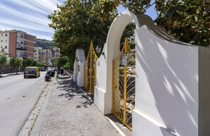 A paved sidewalk adjacent to a building with a white wall and yellow gates. - Holiday Home 'Casa Tina' with Private Pool, Wi-Fi, and Air Conditioning (Sorrento)