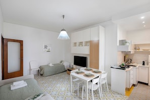 Ein gemütlicher, kompakter Wohnraum mit Küchenzeile, Essbereich, Bett und Fernseher.