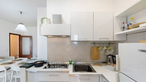 Eine moderne Küche mit weißen Schränken, einem Gasherd, einer Spüle und einem Kühlschrank.