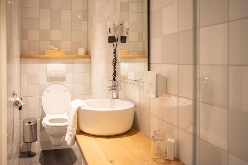 Un baño con inodoro, lavamanos y barra para toallas.