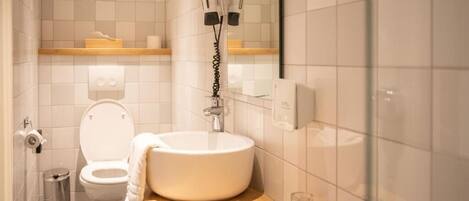 Un baño con inodoro, lavamanos y barra para toallas.