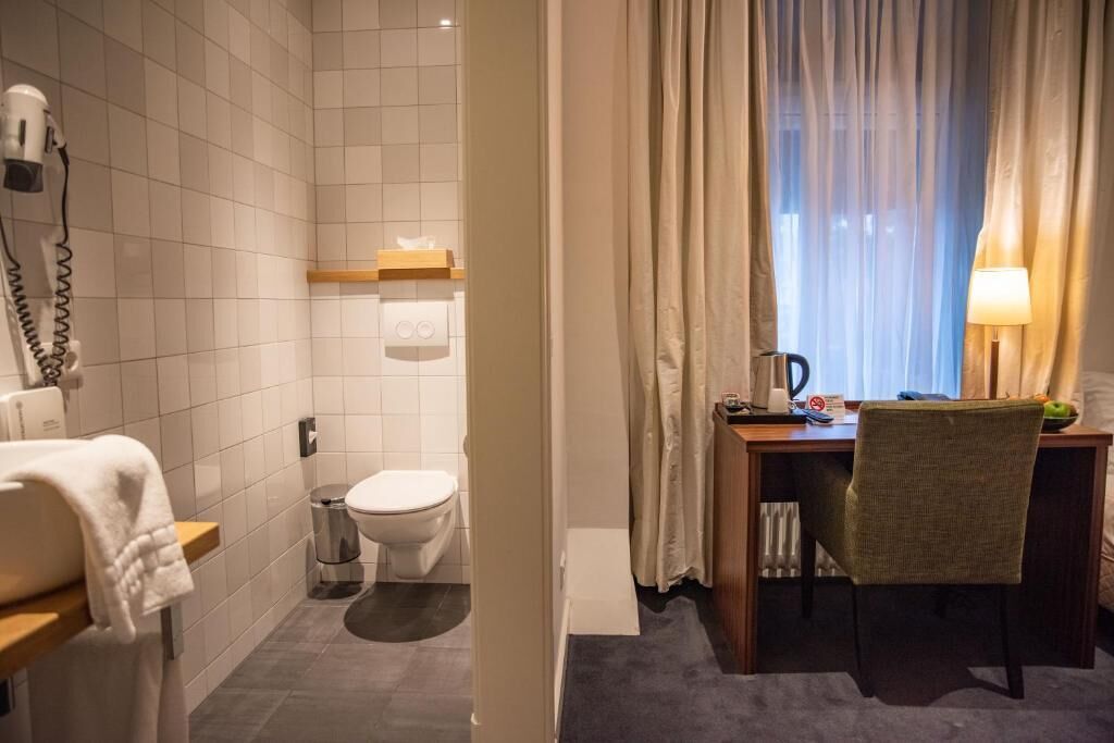 Een badkamer met toilet, haardroger, handdoek en douchegordijn.