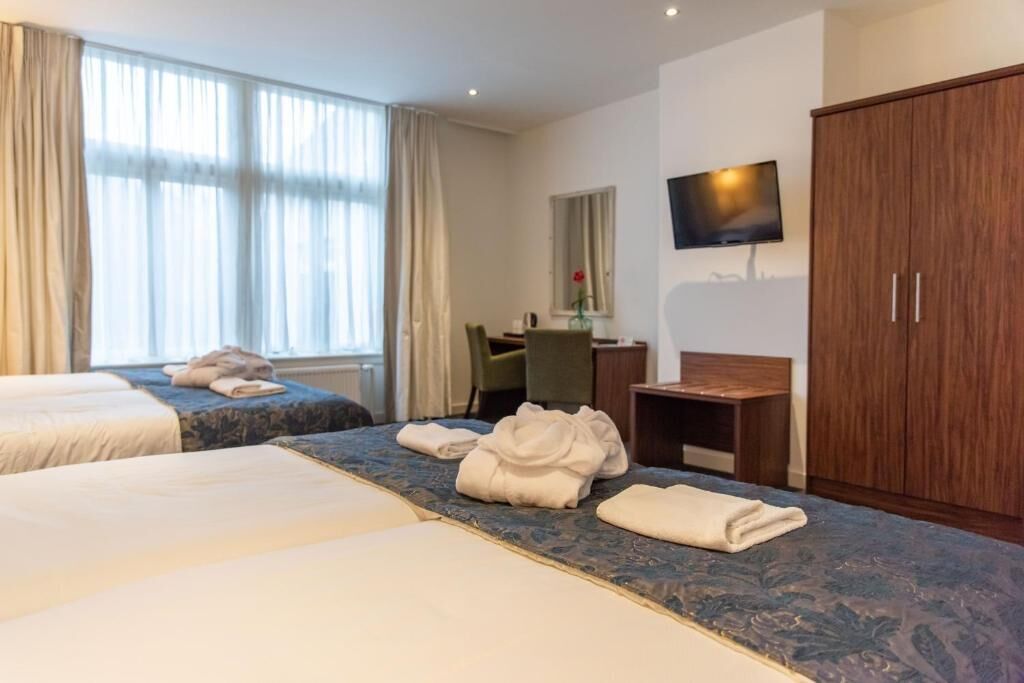 A hotel room with two beds, a desk, a TV, and a wardrobe.