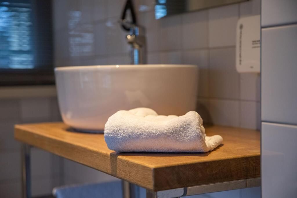 A white ceramic sink on a wooden countertop with a white towel on it.