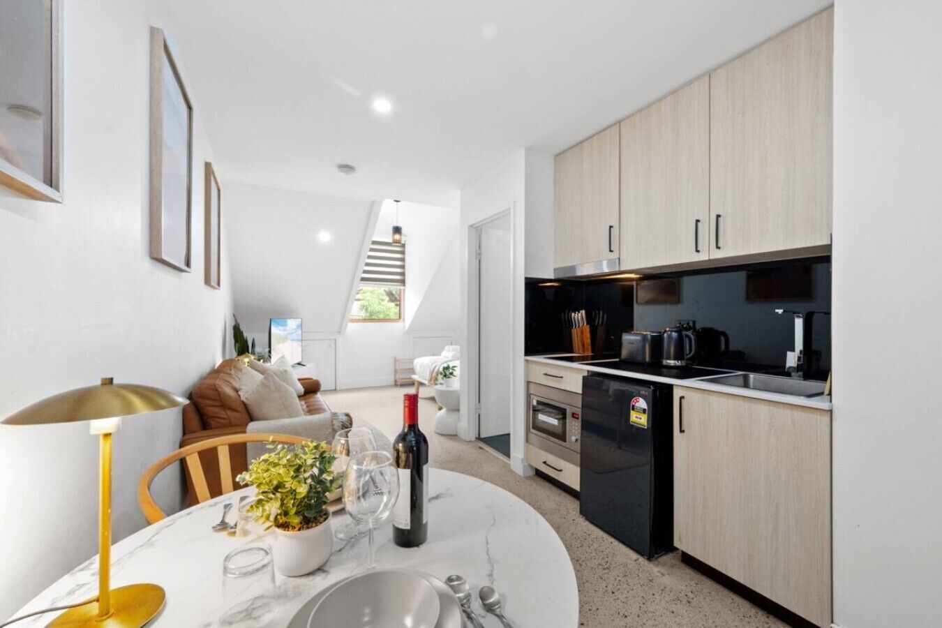 A modern kitchen with built-in appliances, a dining area with a table set for two, and a staircase leading to an upper level.