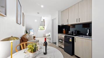 A modern kitchen with built-in appliances, a dining area with a table set for two, and a staircase leading to an upper level.