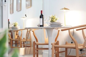 Een modern interieur met houten stoelen en tafels, een wijnfles en een plant in pot op een tafel.