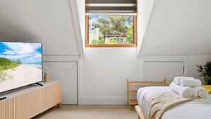 Une chambre avec une télévision, un lit, une fenêtre donnant sur un beau paysage et un plafond en pente.