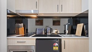 Une cuisine moderne dotée d’appareils électroménagers en acier inoxydable, de meubles en bois et d’un réfrigérateur noir muni d’une étiquette indiquant sa classe d’efficacité énergétique.