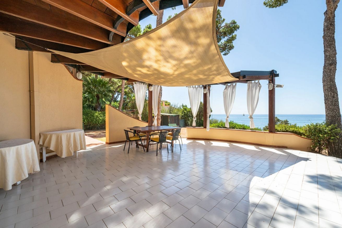 Une terrasse couverte avec une table et des chaises, une vue sur la mer et une structure en forme de pergola.