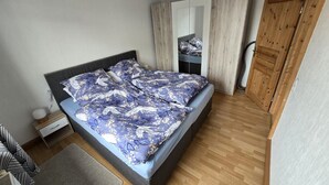 Ein Schlafzimmer mit Bett, Kleiderschrank, Nachttisch und Spiegel.