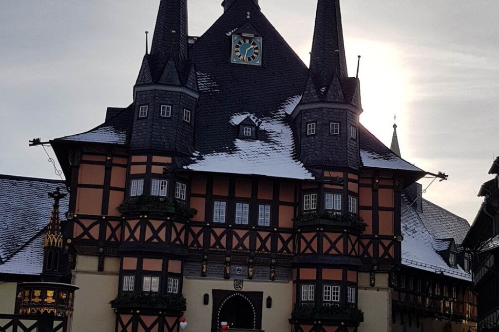 A historic building with a clock tower, multiple windows, and a traditional half-timbered facade.