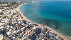An aerial view of a coastal town with a beach, buildings, and a clear blue sea. - Brezza Salentina House Giardino Privato (Porto Cesareo)