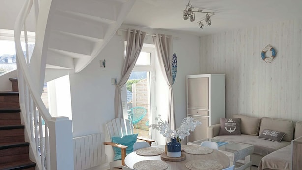 A dining area with a round table, chairs, and a vase with flowers. - Duplex sea view - Terrace - Near the sea - Rated 3*. (Trébeurden)
