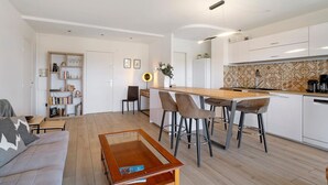 Eine moderne Küche mit weißen Schränken, einem Holztisch und Barhocker.