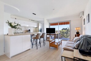 Um espaço de estar moderno com cozinha, área de jantar e sofá com televisão.