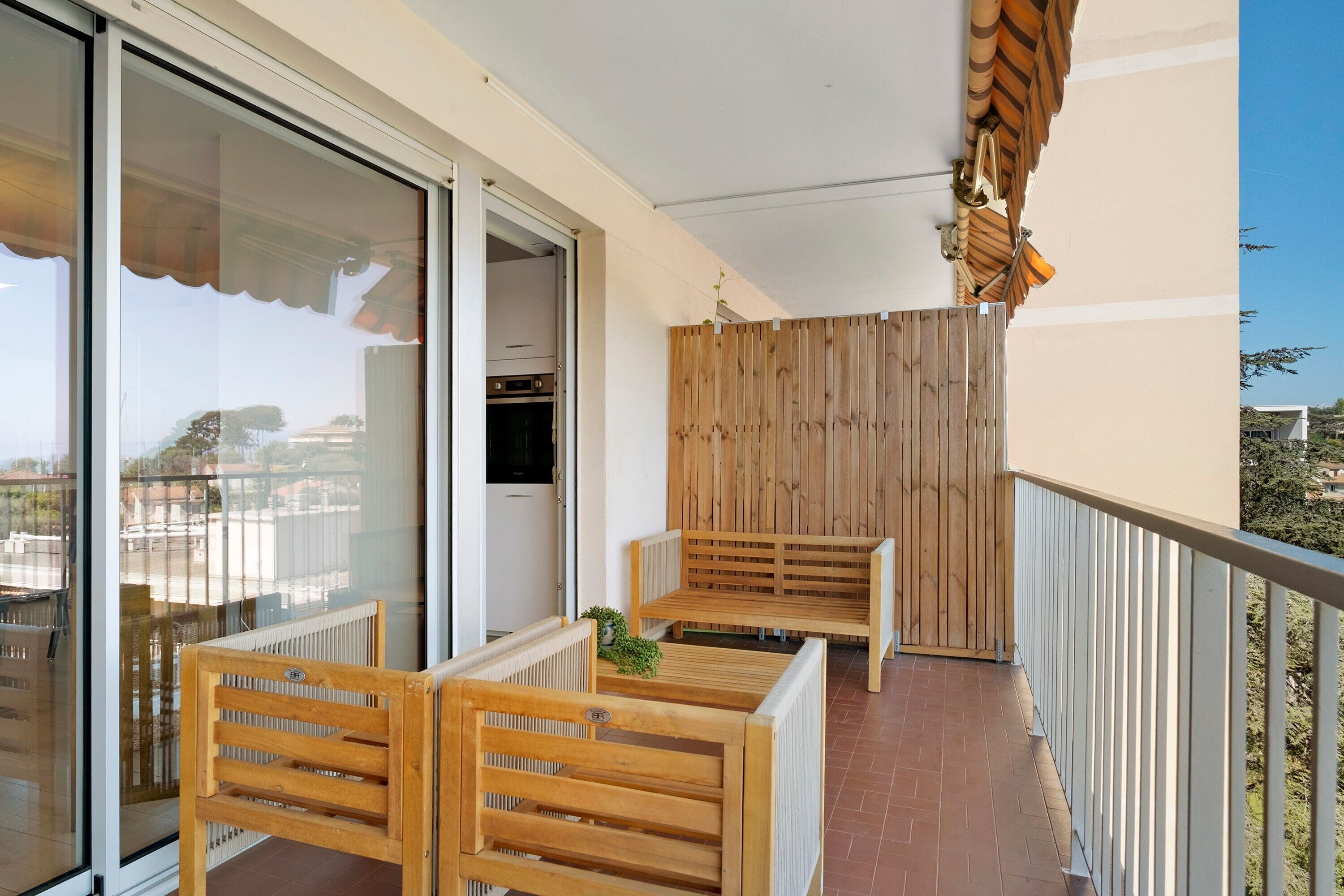 A balcony with wooden furniture, a wooden partition, and a view of the city.