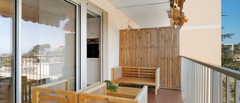 A balcony with wooden furniture, a wooden partition, and a view of the city.