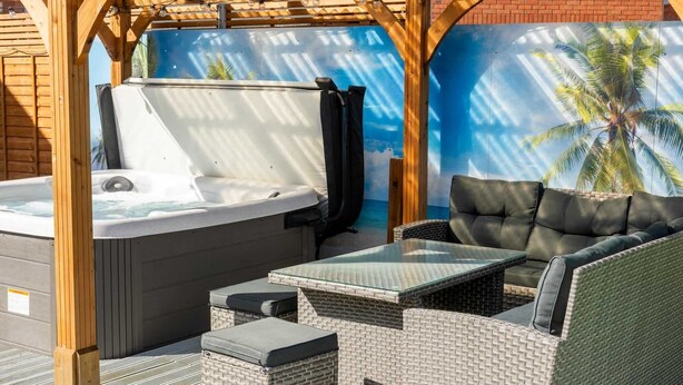 Un bain à remous, un espace salon extérieur et une fresque représentant un palmier.