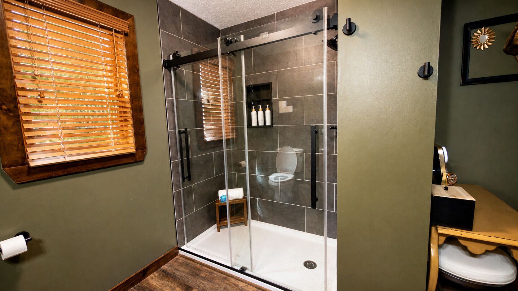 A shower with a glass door, a toilet, and a sink with a mirror.
