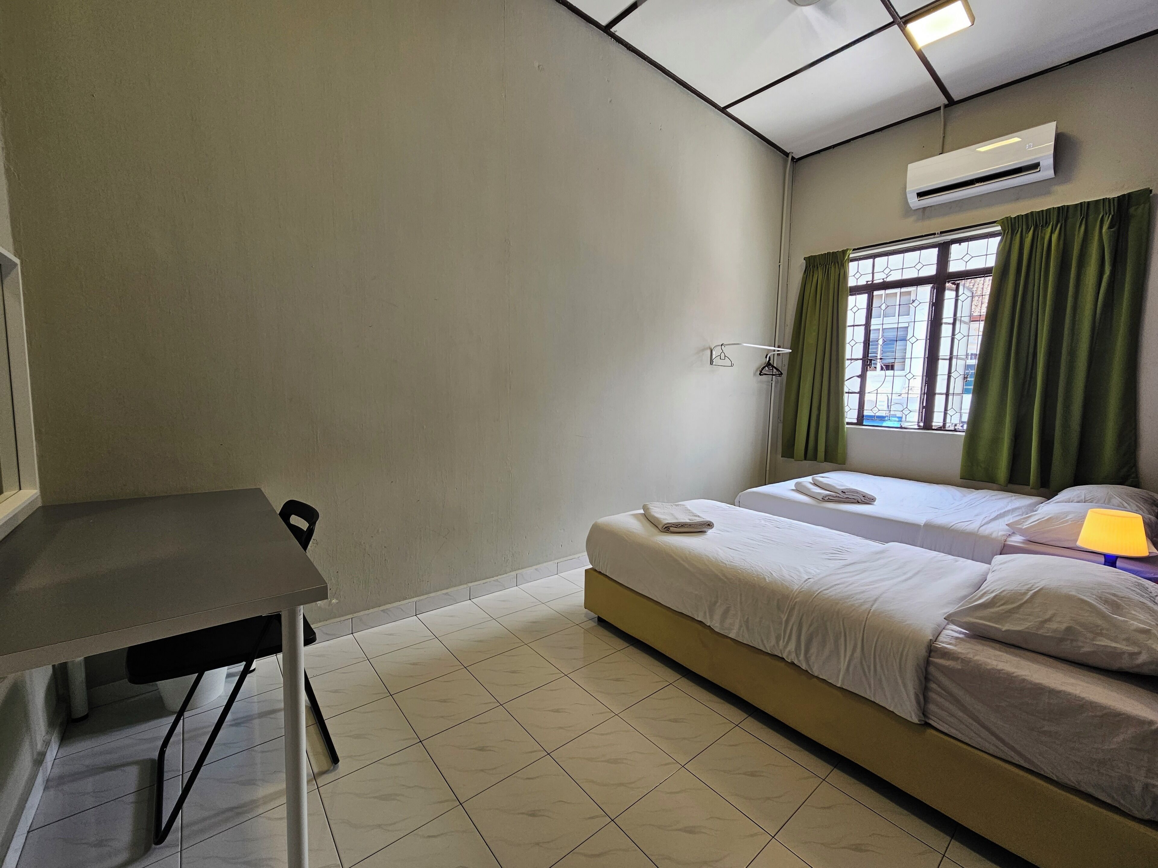 Una habitación con cama, una mesa y un equipo de aire acondicionado.