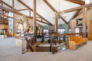 Un hall d’entrée spacieux avec de hauts plafonds, des poutres en bois, un lustre, un banc en bois et un sapin de Noël.