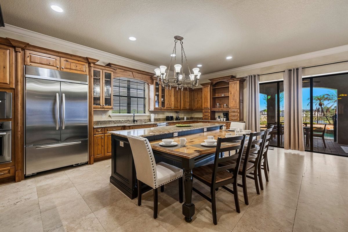 A spacious kitchen with a central island, stainless steel appliances, wooden cabinetry, and a dining area with chairs.