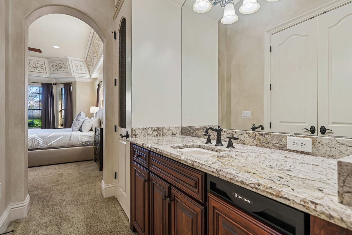 A bathroom with a double sink, dark wooden cabinets, a large mirror, and a light fixture above the mirror.