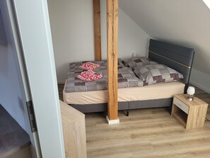 Une chambre à coucher avec un lit, une tête de lit en bois, une table de chevet et une commode.