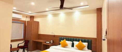 A hotel room with a large bed, a desk, a chair, and a ceiling fan.