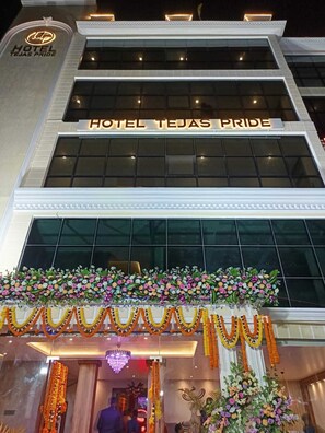 A hotel entrance with a large sign reading 'HOTEL TEJAS PRIDE,' a glass facade, and floral decorations. - Hotel Tejas Pride (Bhadrak)