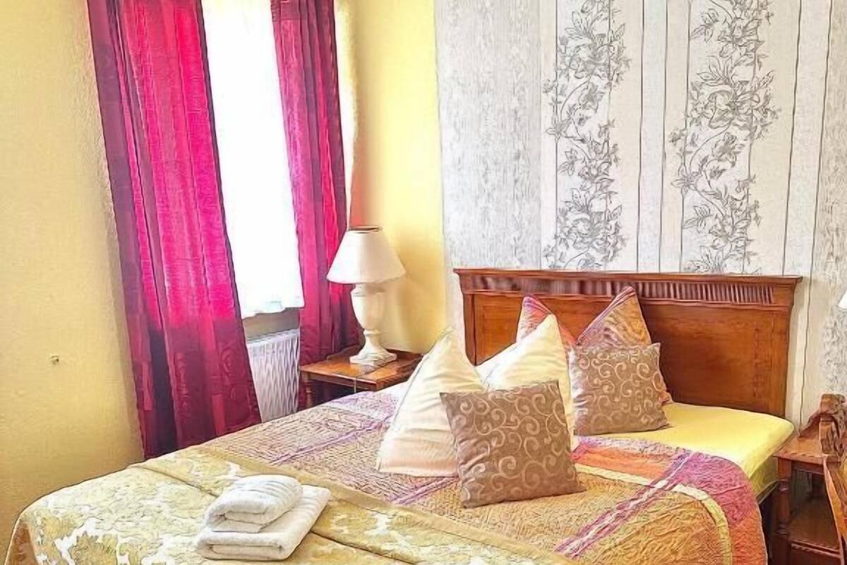 A hotel room with a bed, a nightstand, a lamp, and a floral wallpaper.