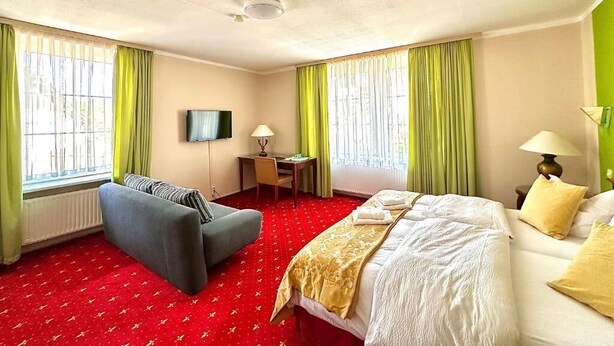 Une chambre d’hôtel avec un lit, un canapé, un bureau et une télévision.