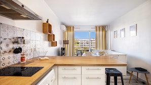 A modern kitchen with a wooden countertop, white cabinets, and a built-in stove. - Air-conditioned studio with sea view and pool (Antibes)