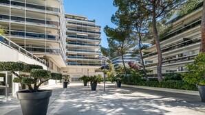 A modern building with multiple balconies, potted plants, and a clear sky. - Air-conditioned studio with sea view and pool (Antibes)